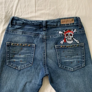 Seeyo jeans - !Köp gärna direkt! Seeyo jeans med dödskalle fram och bak🤍 Några rhinestones som ramlat av bak utöver det fint skick, midjemått:38,5(+stretch) innerbenslängd:81 (Strl L men små i storleken, passar mig som oftast är W28)