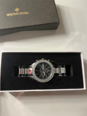 Timothy Stone klocka  - En helt ny timothy stone klocka - Amber bicolor silver-tone & black. T.o.m plasten kvar på klockan, enbart testad. Äkta med bevis och låda. Köpt för 1500kr 