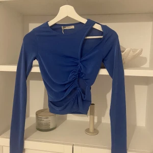 Trendig blå tröja med cutouts - Jättesnygg blå långärmad topp med snygga cutouts. Helt oanvänd! 