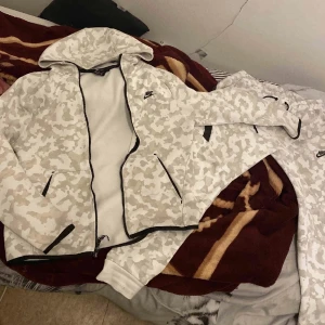 Nike tech camo - Hej! Säljer nu min Nike tech camo i färgen vit. Dressen köptes  för 2000kr. Säljer pga att jag har tröttnat, den är felfri bara att färgen på dragkedjan har lossnat lite. Kan gå ner i pris vid snabb affär. Vid fler frågor eller funderingar  kom privat😇⭐️