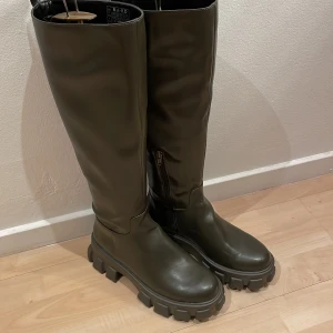 Stövlar - Ett par olivgröna stövlar från Na-kod.Liten skrapa fram,syns knappt.säljes för de är försmå för mig tyvärr.Passar även perfekt till kjolar och stickad tröja t.ex!Nypris 600