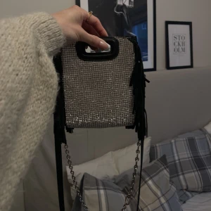 Maje väska limitededition - Intressekoll på min älskade maje väska🤍 glittrig på ena sidan och svart mocka på andra, båda banden kommer även med! Använd men väldigt fint skick då den är behandlad som min bebis, några av stenarna har lossnat i ena hörnet men inget som syns tydligt!