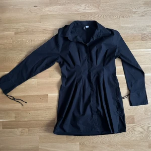 Klänning - Kort långärmad klänning med cool design och snygg passform, fina små detaljer och knappar som inte syns när man tar på sig den. Väldigt bra skick.