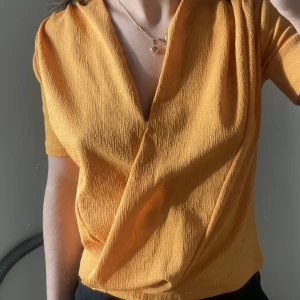 Topp - En orange topp med urringning. Passar xs och s 