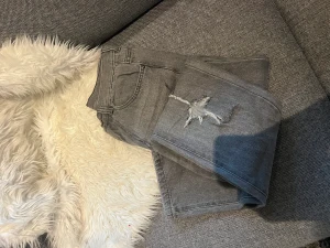 Jeans  - Ett par gråa jeans från ASOS. Hål på ena knät och slits nedtill. I stolek XS. Mycket bra skick! 