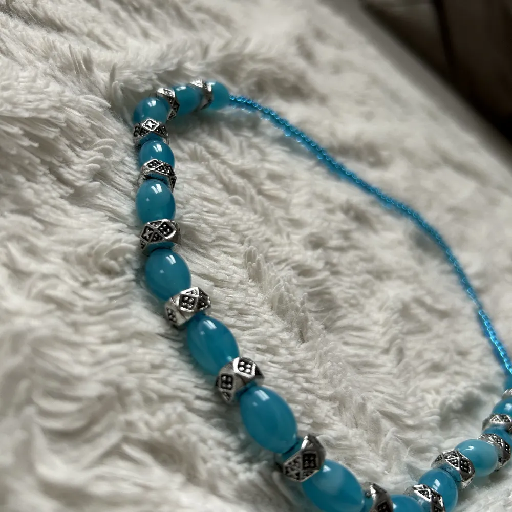 Ett halsband med blåa och gråa stenar💙Det är hemmagjort med töjbar tråd så man får det över huvudet när man ska ta på det🫶🏼10kr + frakt. Accessoarer.