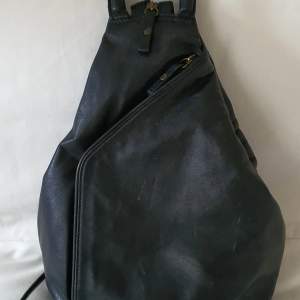 Prada (ej äkta) ryggsäck i supermjukt, svart skinn. Praktisk modell som kan bäras som handväska eller ryggsäck. Använd, med visst slitage på yttre hörn etc. Metalltassar undertill.
