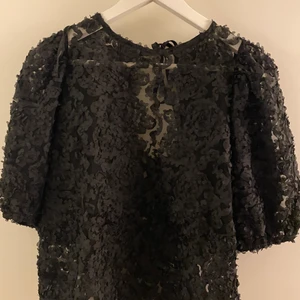 Kortärmad topp, strl XS - Söt, svart, genomskinlig topp med blommönster och knyt där bak,  från Ginatricot. Använd 1 gång. Jätte fint skick. Storlek XS men passar även S.
