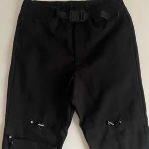 Alyx gaiter pants - Justerbar midja med deras klassiska metallspänne, justerbara spännen vid knäna.  Storlek M, nypris runt 600€. Dessa är 10/10 enligt mig. Skönaste byxorna jag testat https://feature.com/products/alyx-gaiter-pant-w-buckle-black