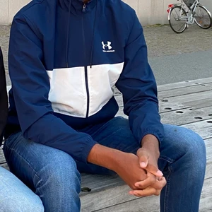 Under Armour - Windbreaker - Tja, säljer denna windbreaker från Under Armour då den blivit för liten. Endast använd några ggr och allting är i utmärkt skick. Den är i st L men passar M också då den är liten i passformen. Köpare betalar frakt - Nypris: 700kr 