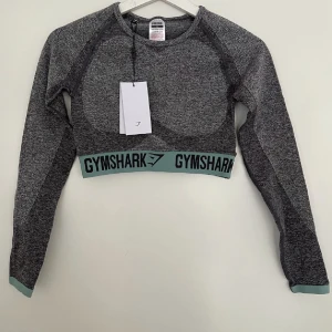 Gymshark strl S - Snygg croppad träningstop från Gymshark. Storlek S. Aldrig använd, lapparna kvar. Superskönt material men har tyvärr inte kommit till användning då jag har väldigt mycket träningskläder. Perfekt för gym och den sitter där den ska under hela passet!