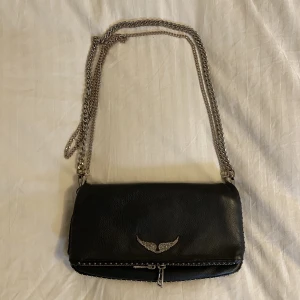 Zadig väska  - Svart Zadig väska i läder med silver detaljer, kommer med två kedjor och kan användas som en axelväska eller crossbody. Inga slitningar på själva väskan, lite färg har försvunnit från silver detaljerna (Detta är mina bilder på min väska!)