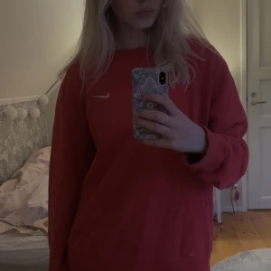 Röd niketröja - En jättefin niketröja. Köpt här på Plick för ca ett år sedan men den är sparsamt använd, inga defekter. Tröjan har ingen lapp där bak så det står ingen speciell storlek. På mig som vanligtvis har s sitter den oversized.