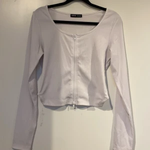 Tröja - Säljer den vita topp med dragkedja som går att dra upp från båda hållen. Använd en gång men säljer den då den är för stor för mig. Tröjan är ribbad och ganska stretchig. 