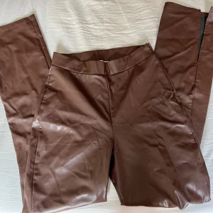 Pu-byxor med slits  - Pu-material med slits på benen som inte syns på bilden, strl small från Nelly. Sparsamt använda och fint skick.💕