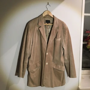 Kavaj/jacka i mocka  - En fin kavaj i beige/ljus mocka och foder av siden av märket Steel, perfekt som jacka till våren. Jättefint skick. Storlek L, mått mellan armhålorna (när den är knäppt): 55 cm, längd: 82 cm. 