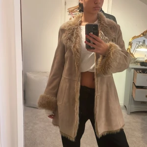 Afghan jacka - Beige afghanjacka i äkta mocka med fuskpäls på muddar, krage och hela insidan.  En söm har gått upp inne i fodret, men påverkar inte användning överhuvudtaget! Inköpt förra vintern men kommit till användning ett fåtal gånger💋