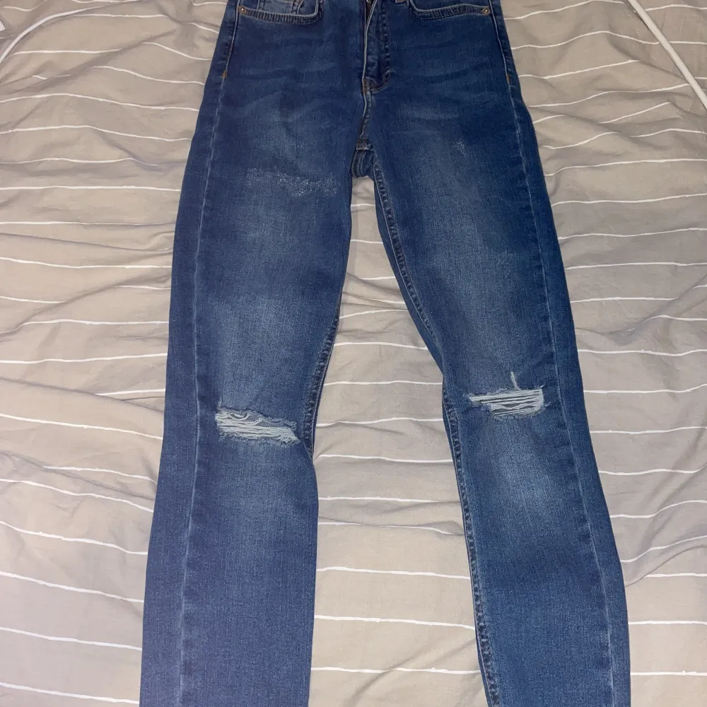 Blåa jeans som är använda 1 gång. Slitningar vid knäna. Stretchiga så passar 32 och även 34. Jeans & Byxor.
