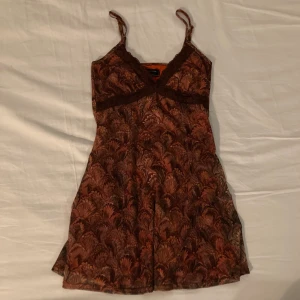 Urban outfitters miniklänning - Säljer denna röda/orangea/bruna mönstrade miniklänning från urban outfitters med spetsdetaljer.