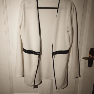 Kavaj  - Fin figursydd kavaj i tunnare strechigt mateial,vit med svart dragkedja.Ok skick.