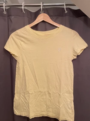 Gul t-shirt från H&M - Super söt gul t-shirt från H&m. Med ett litet hjärt motiv🥰. Säljer det för att jag inte använder det längre. Haft på mig den en eller två gånger. Köpte den för 100kr så säljer för 50kr🥰🥰 