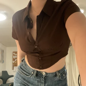 Kort skjorta - Fin kort brun skjorta, perfekt festtopp! Lite stretchmaterial där bak. Finfint skick! Dma för fler bilder eller frågor! 🫂