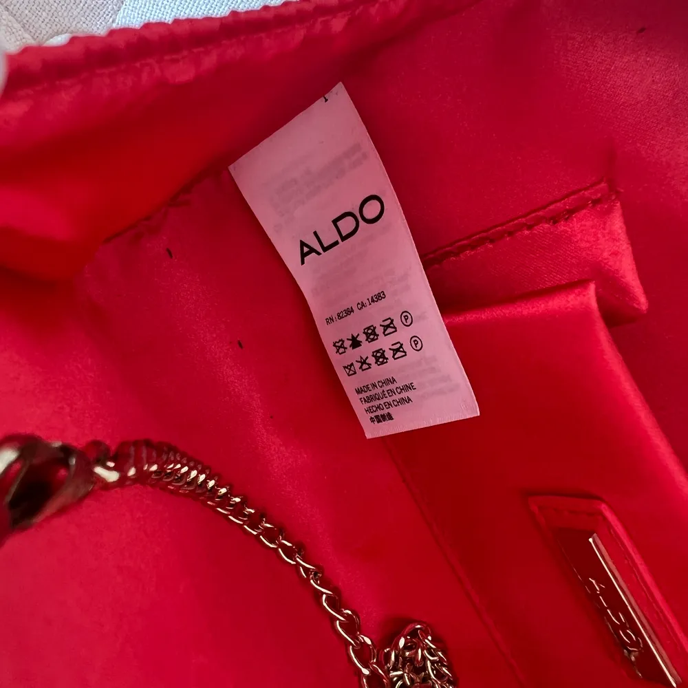 Säljer en röd kuvertväska från märket Aldo. Köpt i en butik i Miami 2016, enbart använd ett fåtal gånger. Säljes pga används ej. . Väskor.