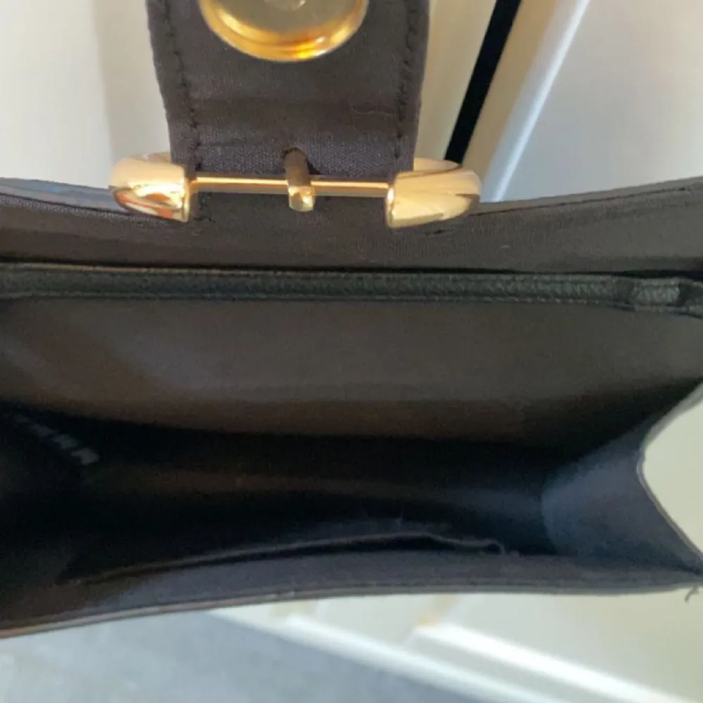 En svart kuvertväskorna med sammetsmaterial utanpå. Guldig kedja och guldigt spänne💕 Mellan stor, får plats med de nödvändigaste. Väskor.