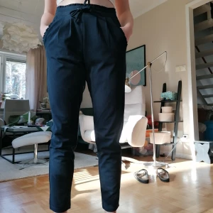 Marinblå kostymbyxa - Slack/kostymbyxa i polyester material. Marinblå och från Jacqueline de Yong. Små volanger i fickor och midja. 