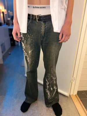 Y2K ’Lost Girl’ Jeans - Utsvängda nedantill.  Dekorerade med pärlor samt hjärtsymboler på alla knappar.