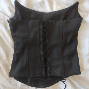 Korsett-topp - Svart korsett, har dragkedja på sidan. Det går att sätta in axelband.  Storlek 38, men går ju att lösa upp eller dra åt så mycket man vill i bak! 💕