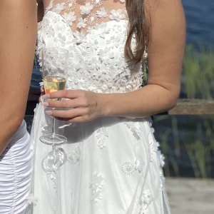 Studentklänning med broderier - Jag säljer min studentklänning då jag inte har fått användning av den efter studenten. Den är otroligt fin med broderade blommor på bröstet samt kjolen. Känns lyxig och är i fin kvalité. Klänningen är hel och fin, endast använd 2-3 gånger. Nypris 1000kr