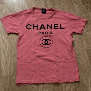 En rosa baby tee med Chanel tryck, står ingen storlek men skulle säga att den passar en S
