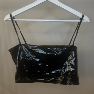 Lacktopp från Nelly - Sååå cool och snygg topp i lackmaterial från Nelly i storlek S. Endast använd en gång, så i mycket bra skick!