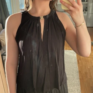 Linne/blus - Svart linne med gulddetalj.