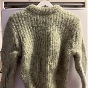 Stickad tröja i alpacka - Ljusgrön/pistage och lite åt de gråa hållet. Har ett ”hårigt” garn som gör den väldigt fluffig