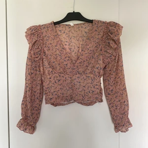 Blommig rosa blus från Shien strl S - Rosa blus med blå och gula blommor från Shien storlek S. Aldrig använd bara testad då den är för kort i ärmarna för mig som är 172cm. Dragkedja i sidan.