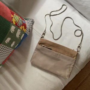 Kuvertväska i skinn Filippa K - Axelremsväska i mocka och skinn från Filippa K. Begagnat skick enligt bild. Ena dragkedjan saknar en läderstropp (se bild). Metallkedjan är fin utan några märken eller missfärgningar. Ca 17 x 13 cm stor. 