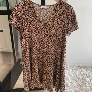 Blommig vinröd/beige klänning weekday - Snygg blommig klänning från weekday i storlek XS. Sitter bra på mig som är S. Använd ett fåtal gånger