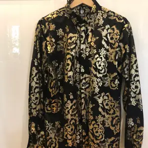 Twisted Tailor herrskjorta i svart och guld, storlek M. Material polyester.