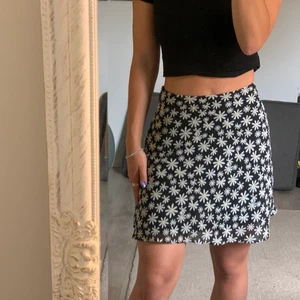 Svart blommig kort kjol  - Säljer denna kjol då den bara har använts  1 gång, köptes förra sommaren. Är i nyskick, väldigt gullig och skönt att ha på sig när det är lite varmt ute. Bara att skriva för fler bilder eller frågor. Köparen står för frakt 