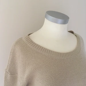 Beige stickad tröja - En ljust beige stickad tröja med bred urringning. På mig slutar den under naveln. Den har en liten fläck, se bild, men den borde gå bort med ett bra fläckborttagningsmedel. 