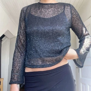 Glittrig topp - Glittrig top i färgen svart från Gina Tricot. Den är i ett genomskinligt material så bilderna är tagna med ett linne under. Endast använd en gång💫