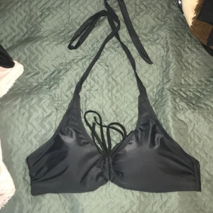 Svart bikiniöverdel - En svart bikini överdel i fint skick! Går att ha banden både runt nacken och knyta fast så de sitter ”över axlarna”! Snörning imitten som går att anpassa!