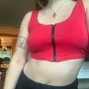 Rött linne med svart dragkedja - Skönt crop-top-linne. Säljer då jag inte använder det längre. Dragkedjan går att dra upp.