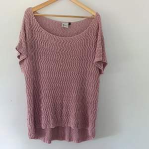 En stickad tröja i rosa. Begagnad, i bra skick. Inga hål. Passar bra med en skjorta under eller som en klänning, ca. 75cm lång i bak.