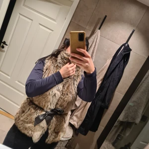 Pälsväst med hög krage - Härlig snygg pälsväst med fickor och hakor till knäppe.  Finns med ett bälte, men det är inte i bra skick, lägger med det ändå.