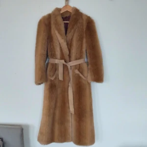 Lång pälskappa - Beige kappa, jag tror att det är fuskpäls och den har mocka tyg på underarmarna men det syns typ aldrig  Skärpet går att ta bort, den går ner till vaderna 