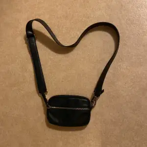 En svart handväska som är rätt så använd. Men ser ut som ny stick. Super bra väska om man ska åka och shoppa och kunna ha sin mobil där i.