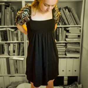 Zebramönster/svart klänning - Kort klänning med zebramönstrade puffärmar. Jättesöt och festlig. Passformen är nog S eller som det står på lappen, 38. Nyskick, knappast använd.